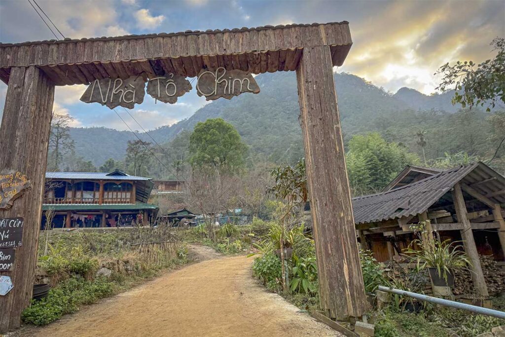 Entrance gate to a homestay in Sin Suoi Ho village with wooden houses and mountain scenery