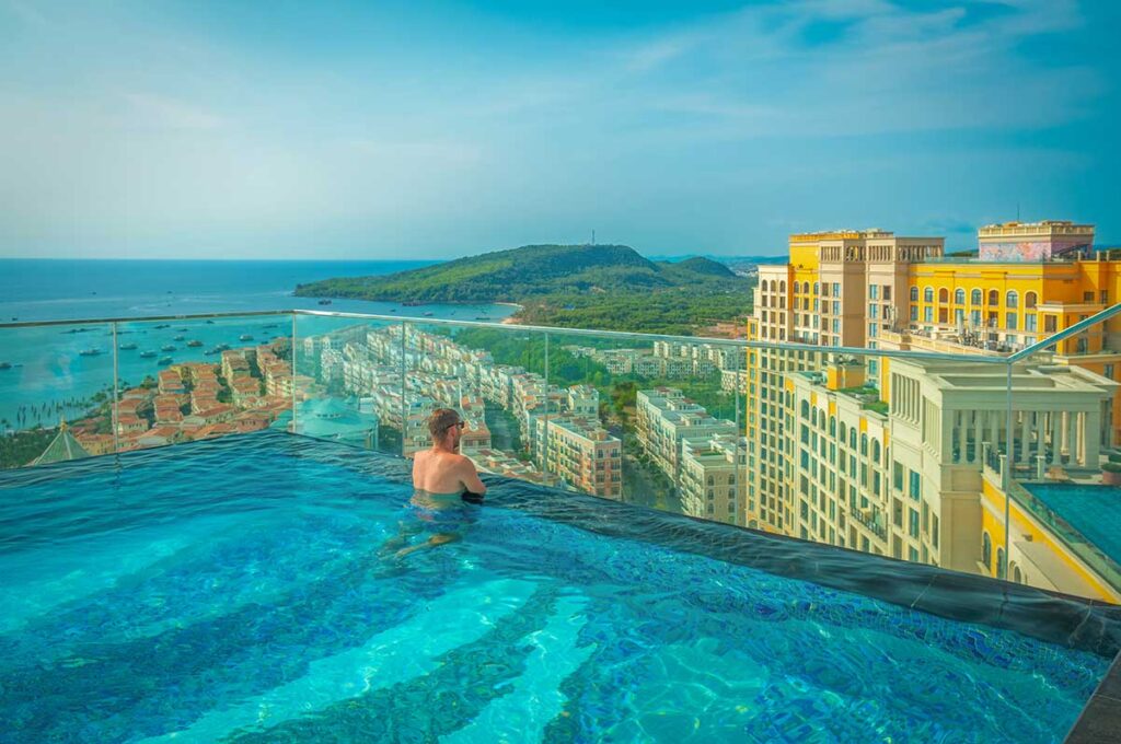 Infinity pool in Sunset Town Phu Quoc hotel with panoramic sea view and coastal town buildings
