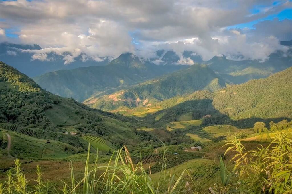 Panoramic view of rice fields and mountain valleys around Sin Suoi Ho with clouds hanging low over the hills