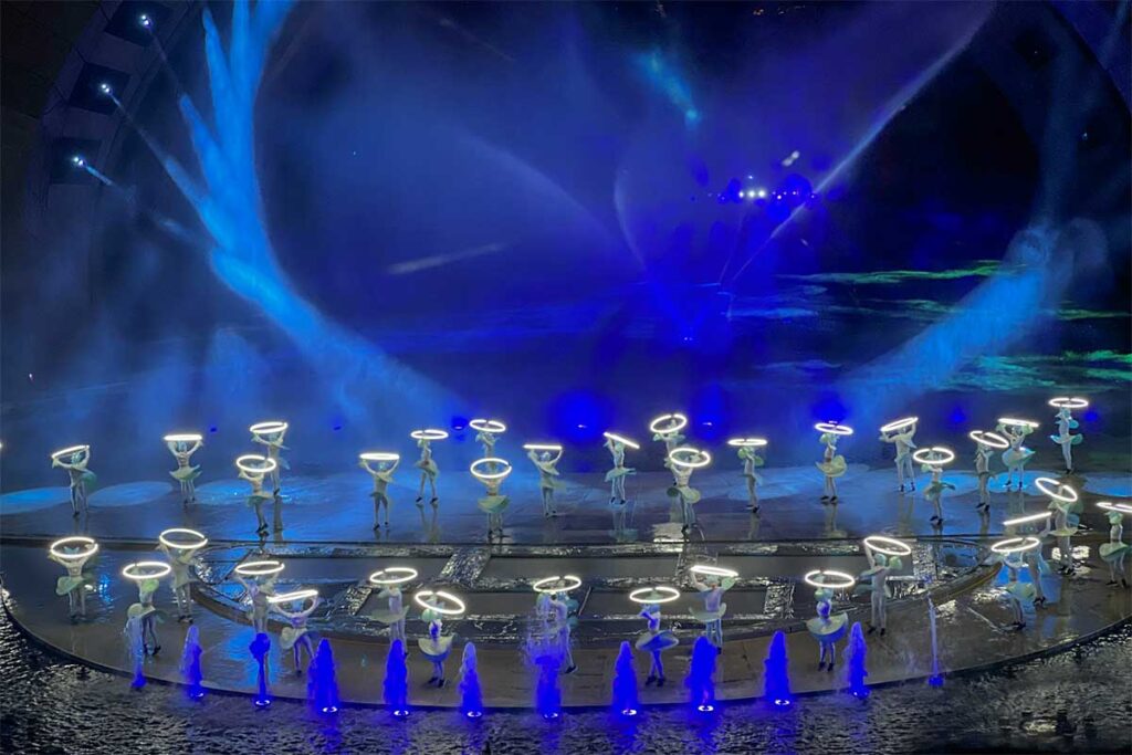 Kiss of the Sea light show in Phu Quoc with performers holding glowing rings on a water stage with blue lighting