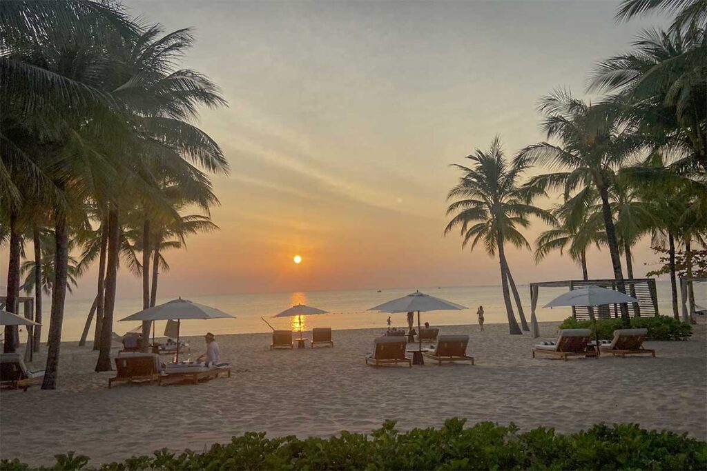 Long Beach Bai Truong Phu Quoc sunset view with palm trees beachfront loungers and luxury resort beach area