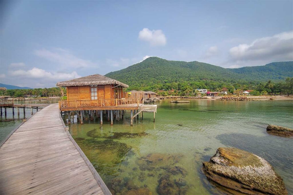 Cay Sao Beach Phu Quoc overwater bungalow with wooden walkway clear sea and green hills