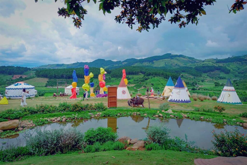 Mongolian-style tents and colorful sculptures at Mongo Land Dalat with mountain views and a small pond in the foreground