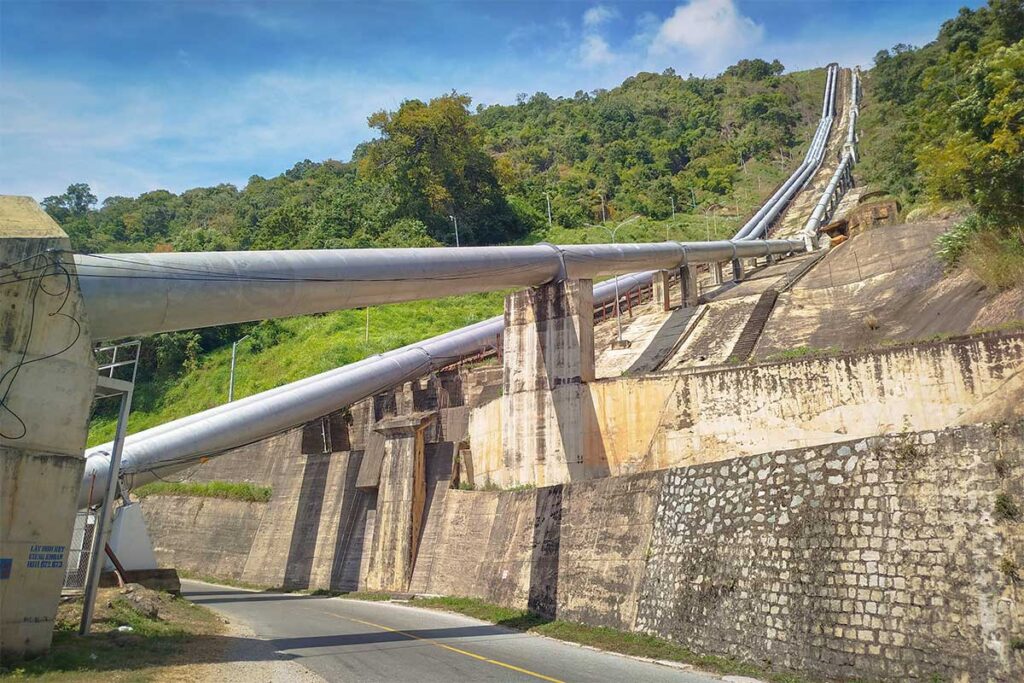 Large hydropower pipes of the Da Nhim system running down the mountainside along Ngoan Muc Pass, crossing above the road