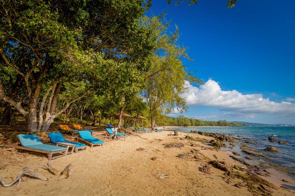 Sun loungers on rocky sandy section of Ong Lang Beach Phu Quoc with tropical shade