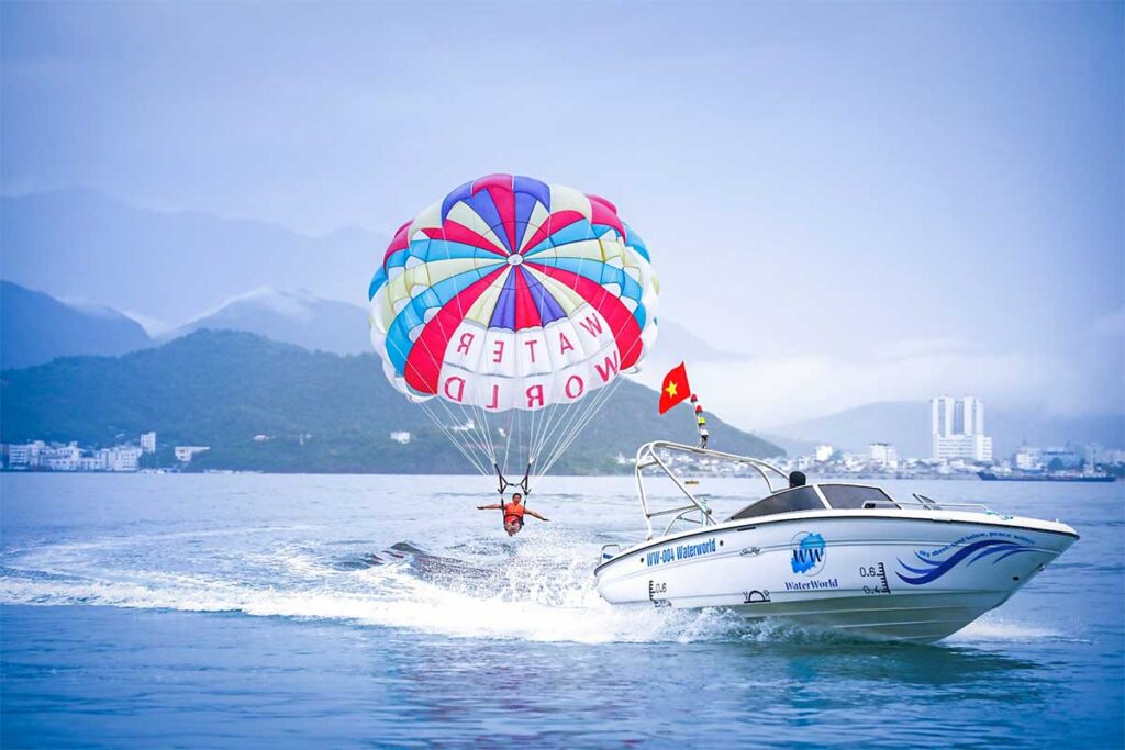 Parasailing at Bai Dai Beach Phu Quoc with speedboat and mountain views in the distance
