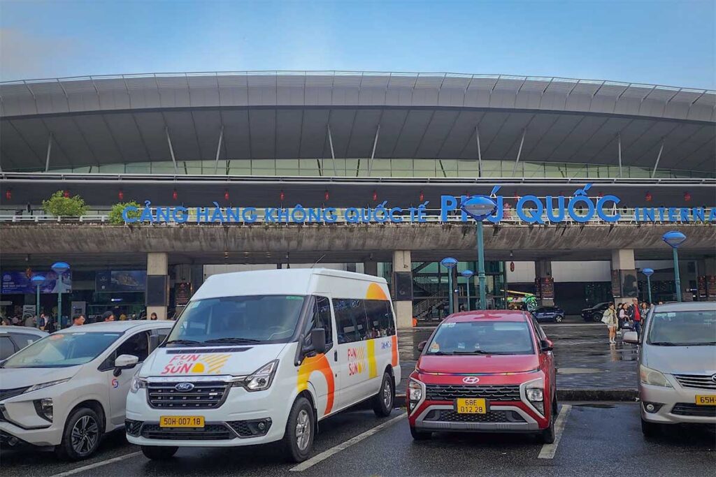 Resort shuttle van and private cars outside Phu Quoc Airport terminal entrance