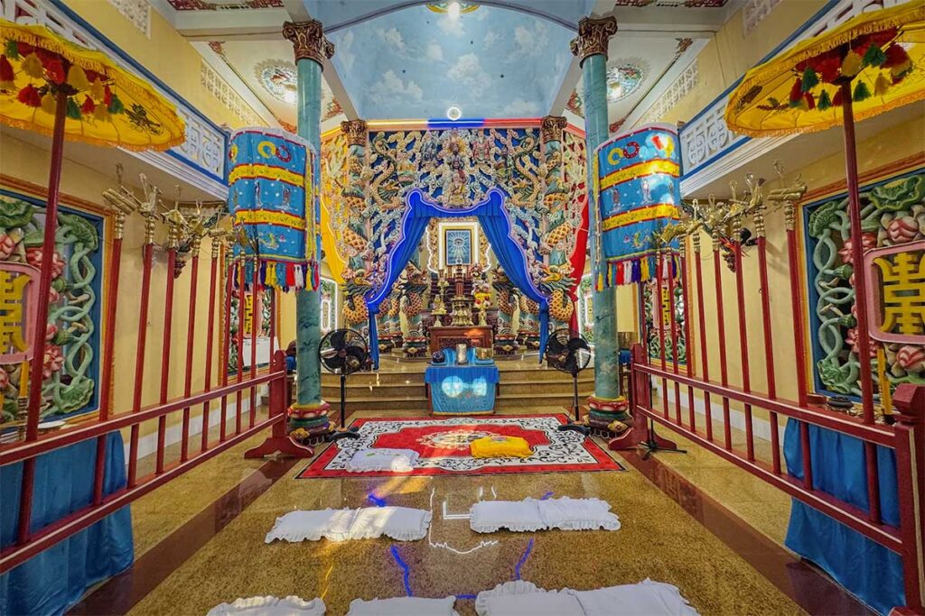 Colorful prayer hall inside Cao Dai Temple in Phu Quoc with altar columns and ceremonial floor cushions
