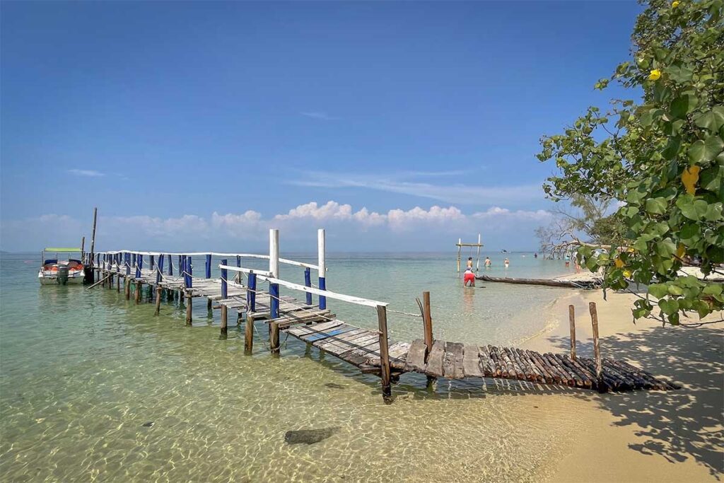 Wooden pier and speedboats in clear water at Starfish Beach Phu Quoc