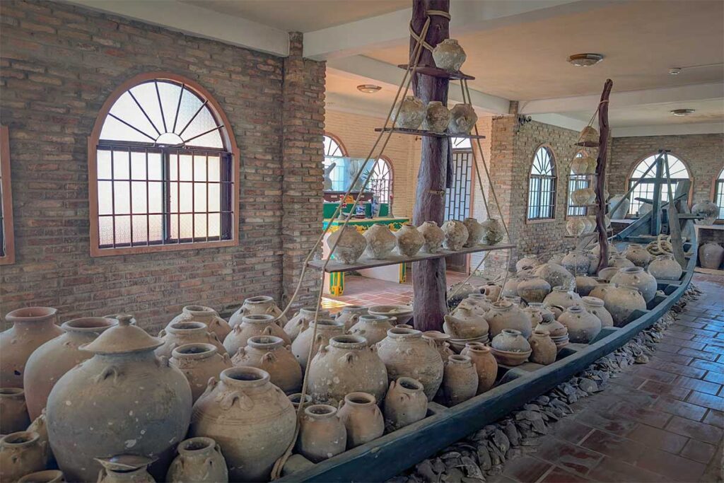 Large ceramic jars displayed in wooden boat inside Coi Nguon Museum Phu Quoc featuring historical trade artifacts