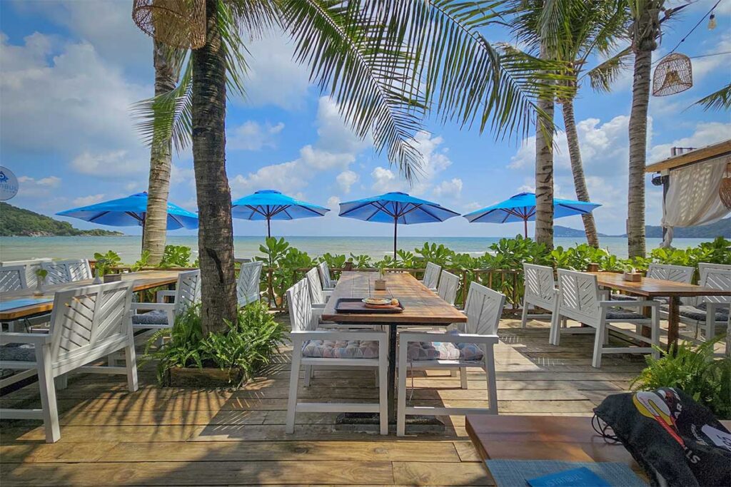 Beachfront restaurant at Khem Beach Phu Quoc with sea view tables palm trees and blue umbrellas