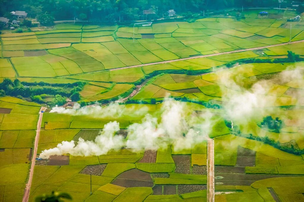 rice fields in Vietnam with farmers burning crops creating smoke and seasonal air pollution