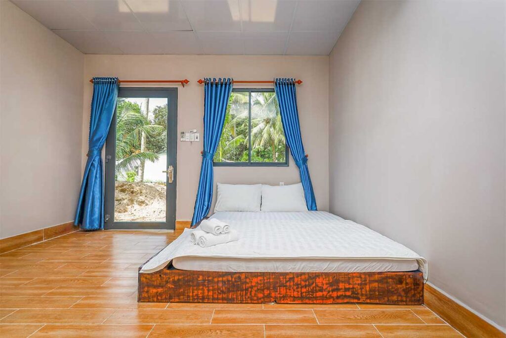 Simple guest room near Bai Thom Beach Phu Quoc with bed tiled floor and tropical garden view