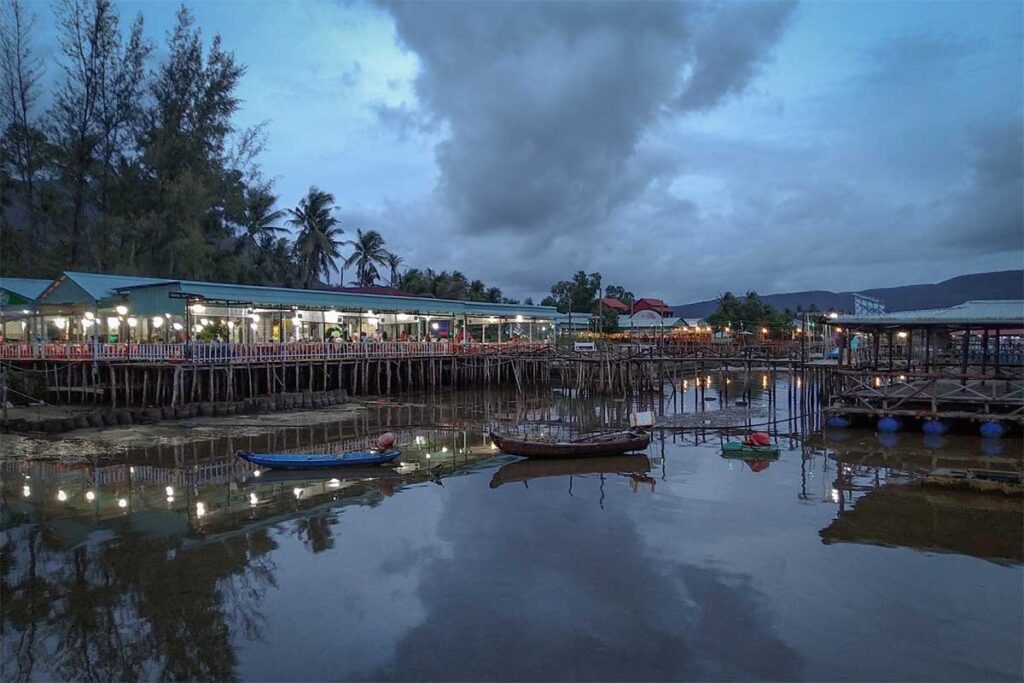 Seafood restaurants in Ham Ninh fishing village Phu Quoc at dusk with boats and reflections on the water
