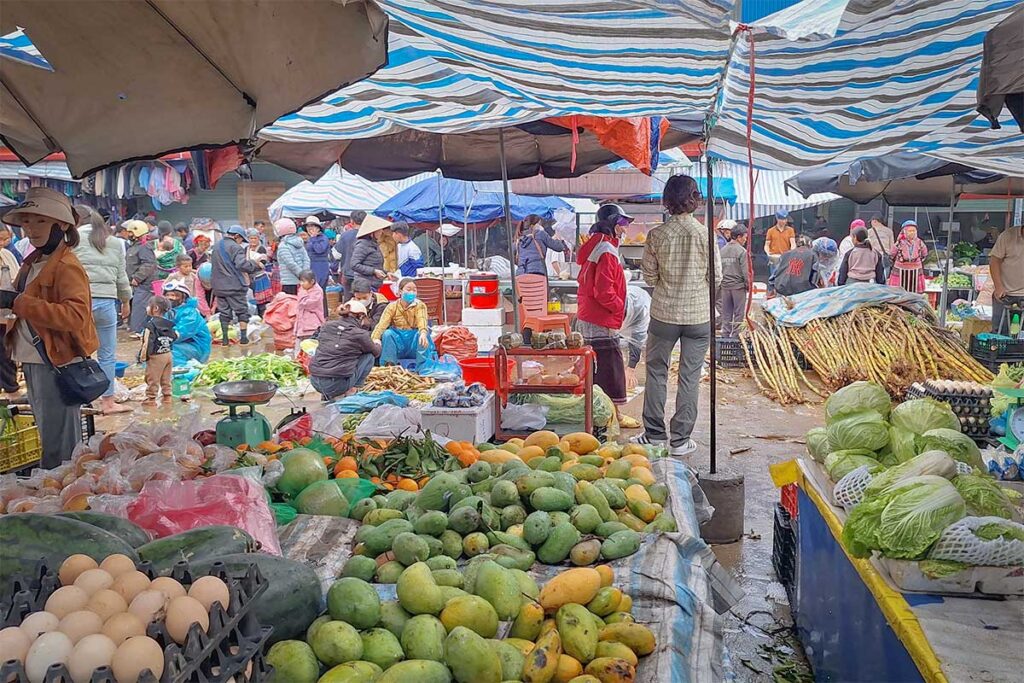 Busy weekend market in Sin Ho with fresh produce, vegetables, and local people shopping under temporary stalls in Lai Chau Province