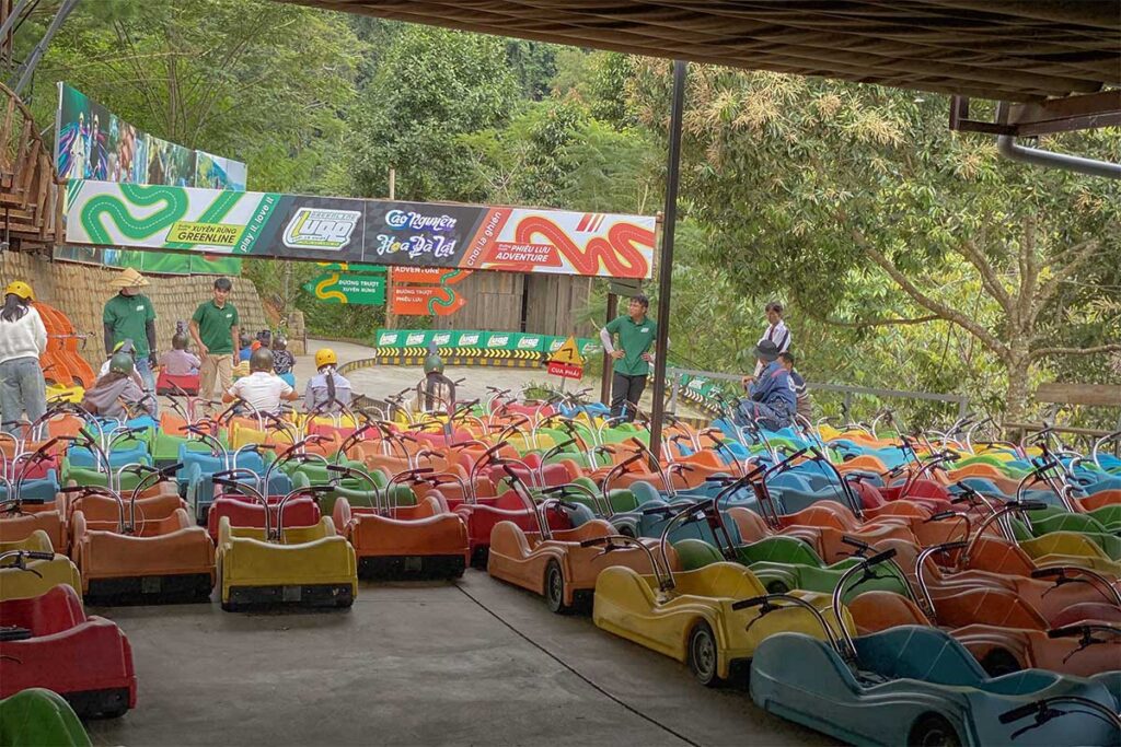 Start area of the Green Line luge track at Mario Kart Dalat with rows of carts lined up and staff preparing visitors