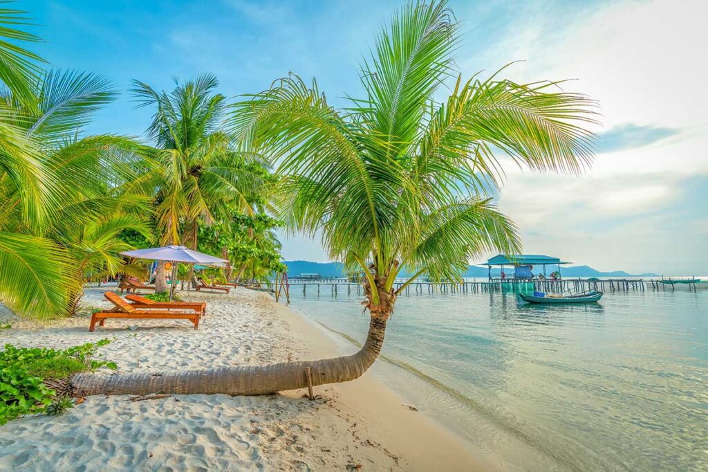 Sun beds and palm trees on white sand beach with floating restaurants at Rach Vem Starfish Beach Phu Quoc