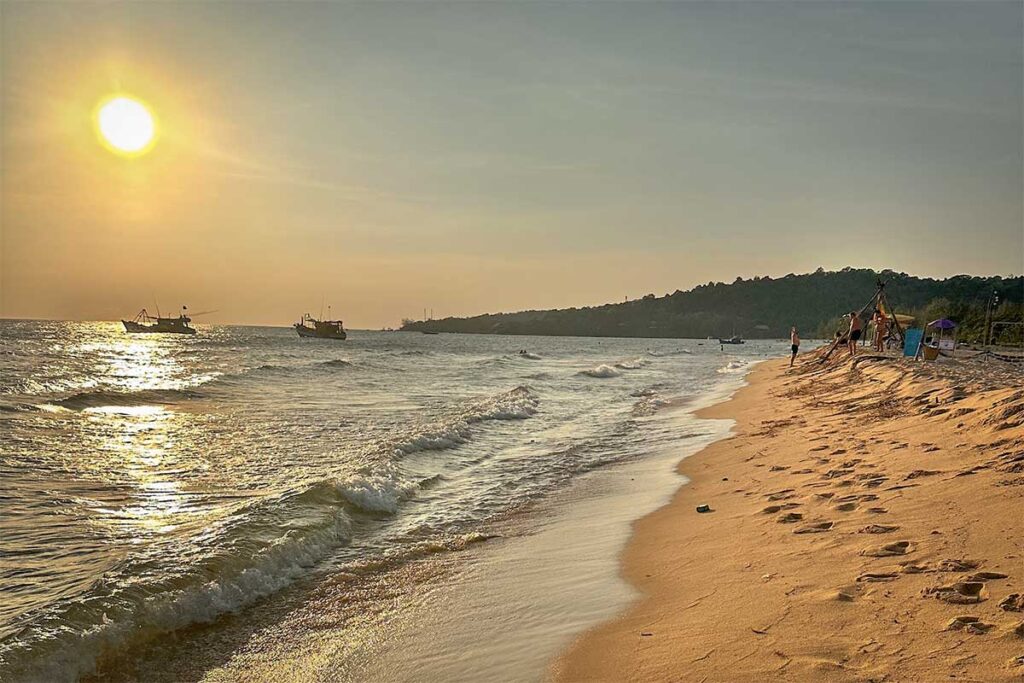 Cua Can Beach Phu Quoc sunset with golden light waves sandy shore and fishing boats at sea