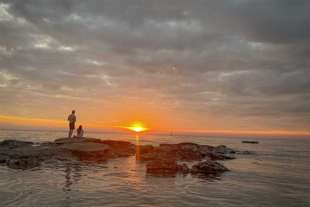 Sunset view from rocky shore at Ong Lang Beach Phu Quoc with people watching the sea
