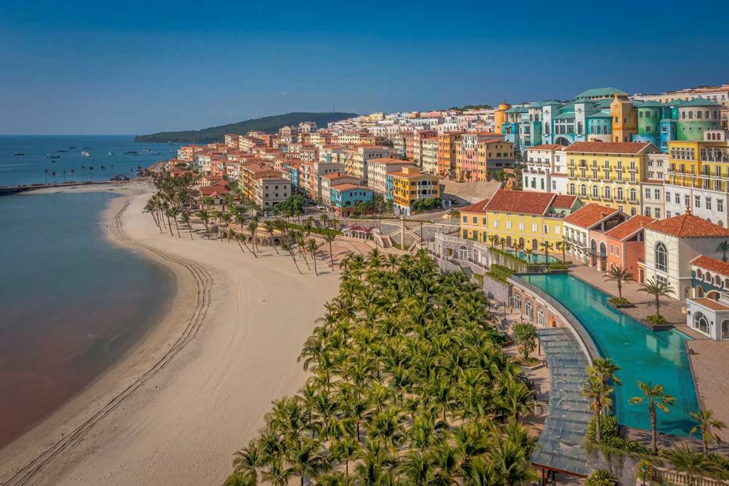 Wide sandy beach in Sunset Town Phu Quoc with palm trees calm sea and colorful buildings along the coast