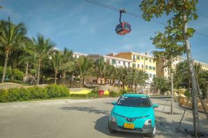Green SM taxi in Phu Quoc parked near Sunset Town with cable car above on sunny day