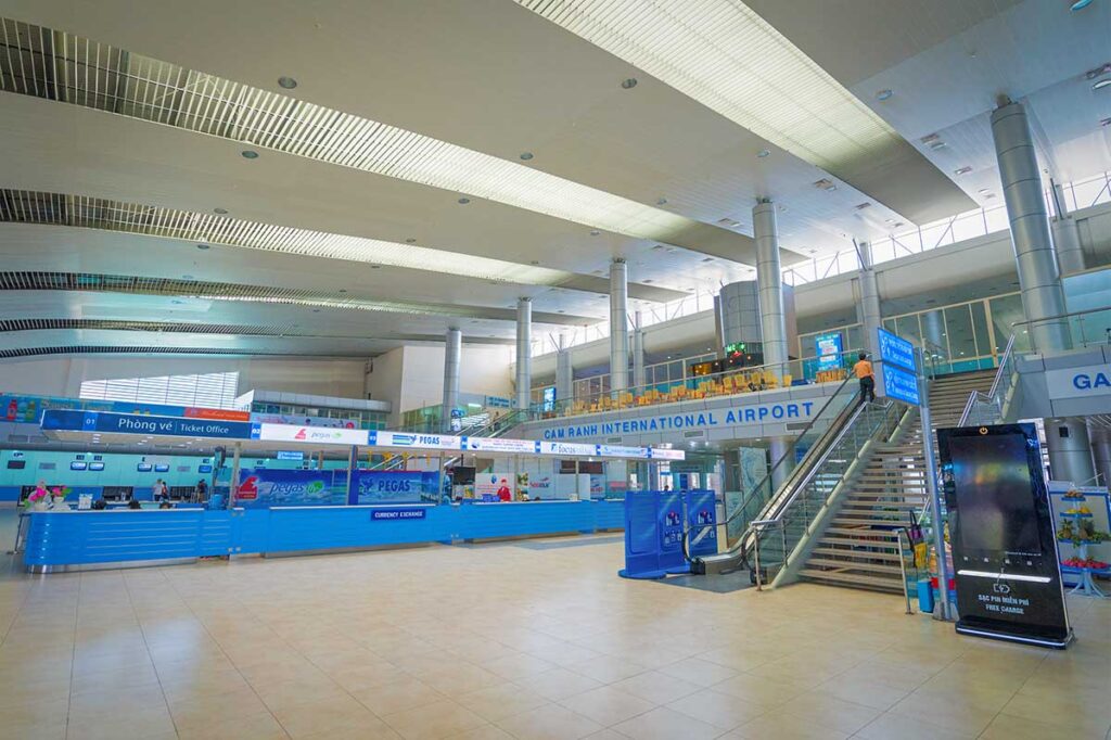 Spacious terminal hall of Cam Ranh International Airport with check-in counters, escalator and seating area for passengers