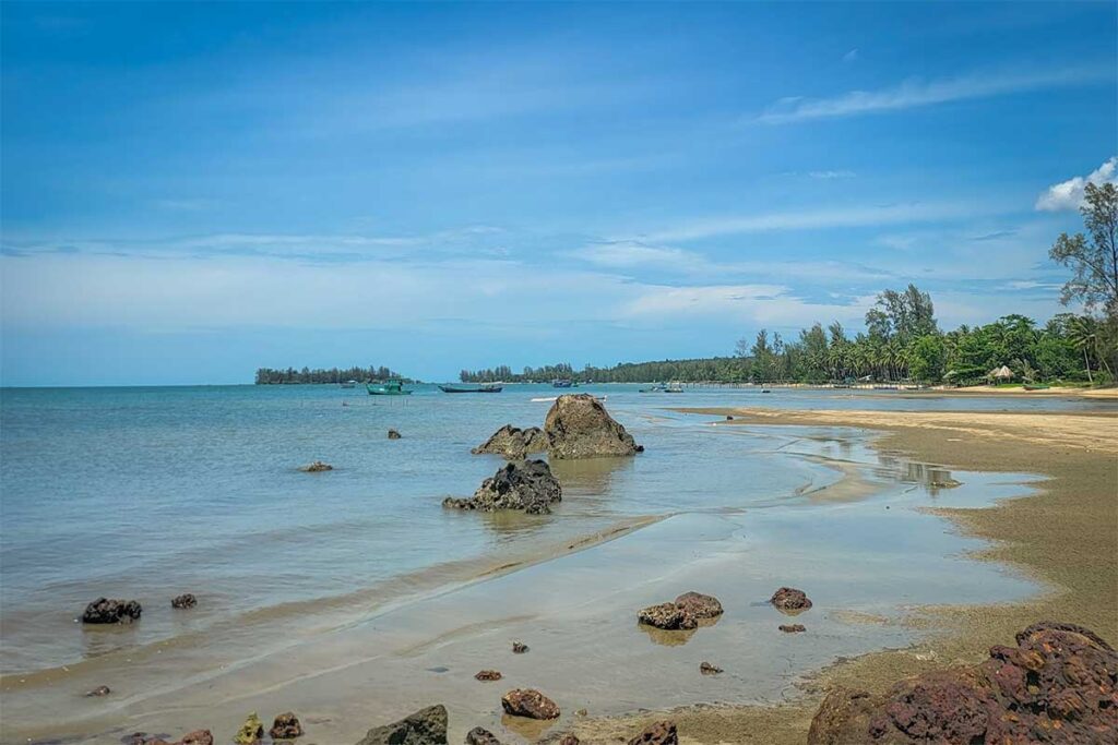 Wide shallow beach at Bai Thom Beach Phu Quoc with rocks fishing boats and peaceful coastline