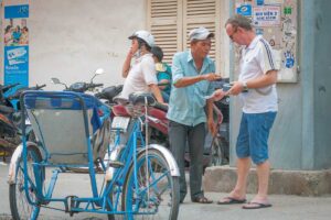 Tourist paying a cyclo driver on the street in Vietnam, a common situation where prices should be agreed in advance