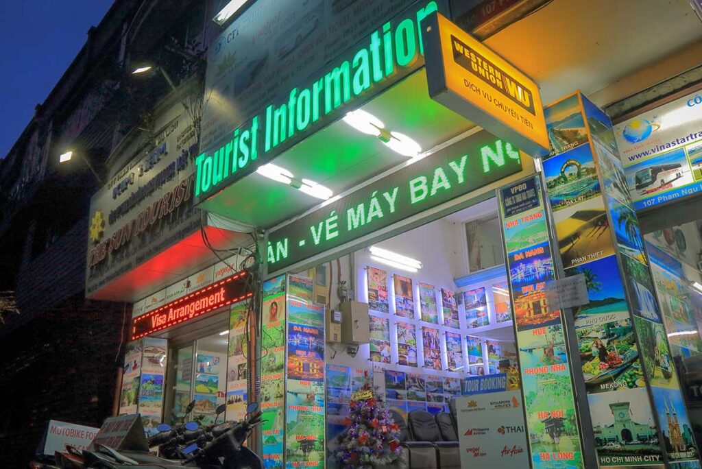 Small travel agency in a backpacker area of Ho Chi Minh City displaying tour options and transport tickets for travelers