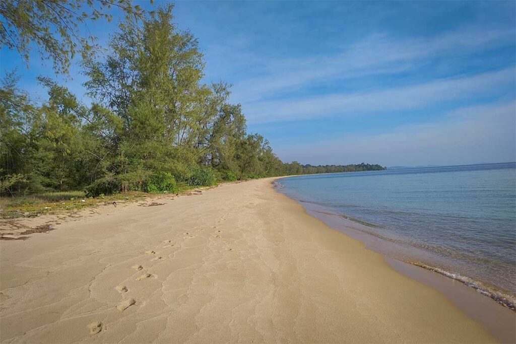 Quiet empty shoreline at Vung Bau Beach Phu Quoc with soft sand footprints and calm sea water