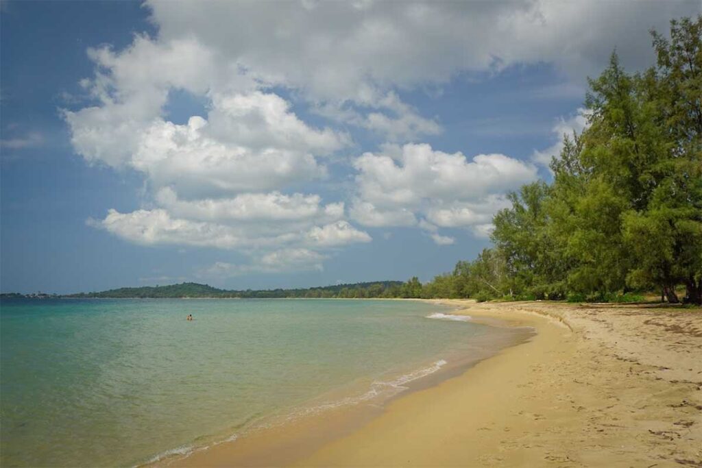 Wide sandy bay at Vung Bau Beach Phu Quoc with calm turquoise water and trees along the shore