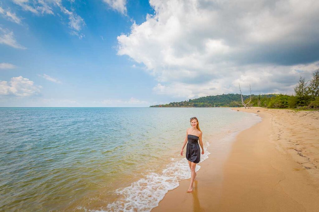 Woman walking along Cua Can Beach Phu Quoc with clear sea sandy shore and peaceful coastline