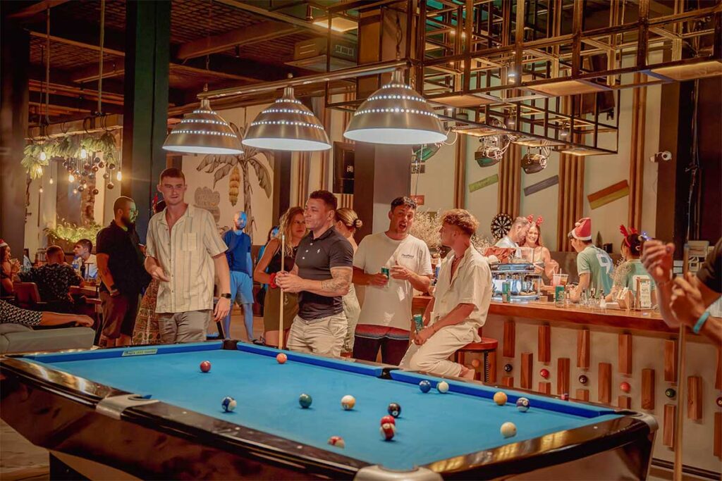 Backpacker nightlife at a hostel bar in Phu Quoc with travelers playing pool, social drinks, and lively evening atmosphere