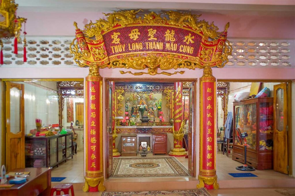 Main altar inside Dinh Ba Thuy Long Thanh Mau Temple in Phu Quoc with red and gold decorations statues offerings and traditional Vietnamese shrine setting