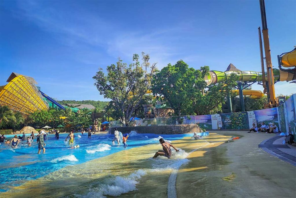 Aquatopia Water Park Phu Quoc wave pool with people playing in shallow waves and slides in background