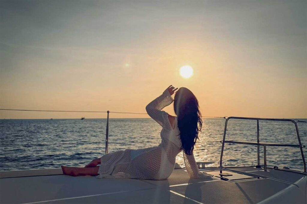 Sunset catamaran cruise in Phu Quoc with woman relaxing on the yacht deck and ocean sunset views during an evening boat trip