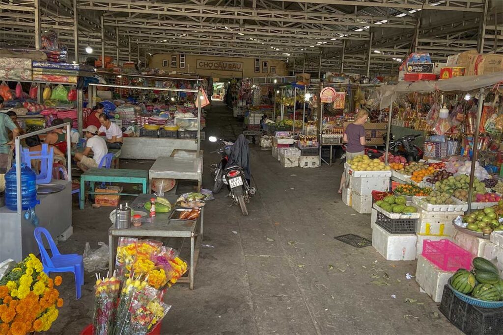 Inside Cau Sau Market in Phu Quoc with local fruit stalls flowers household goods and traditional market aisles used by residents and visitors