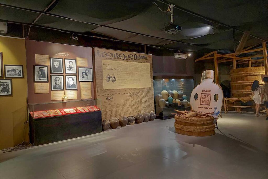 Exhibition room at Lang Chai Xua Fish Sauce Museum displaying historical fish sauce ceramic jars, old newspaper clippings and portraits of Phan Thiet fish sauce producers