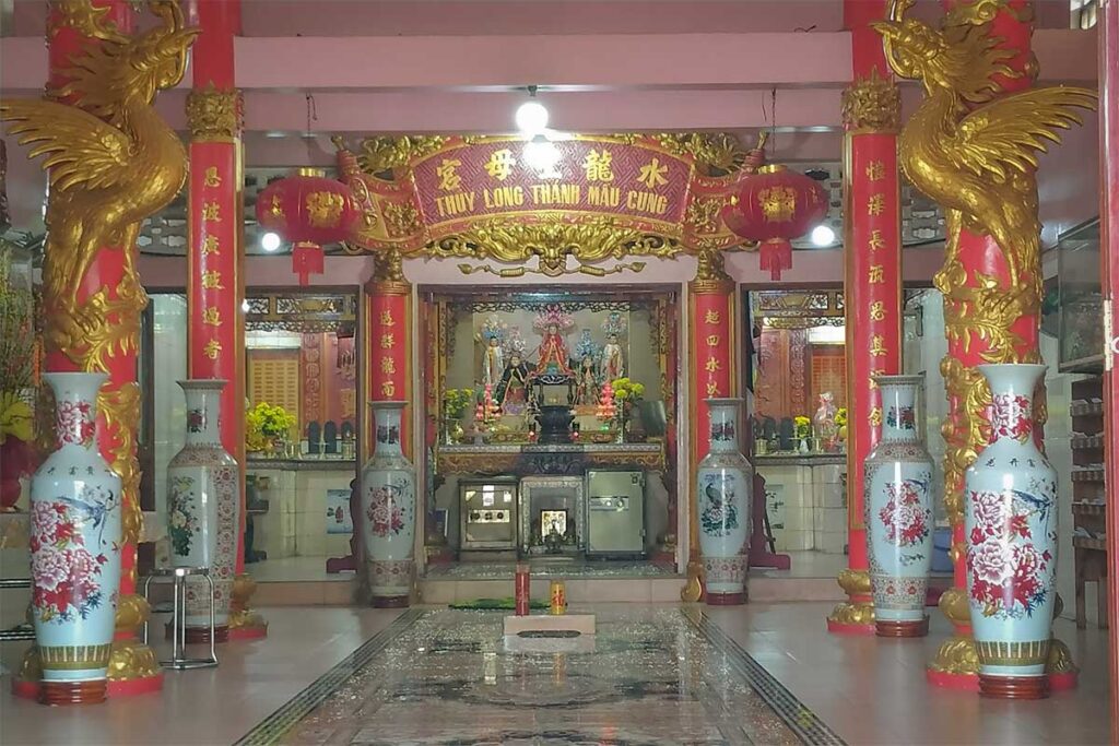 Interior of Dinh Ba Thuy Long Thanh Mau Temple in Phu Quoc with altar large ceramic vases red pillars and decorative carvings in a symmetrical layout