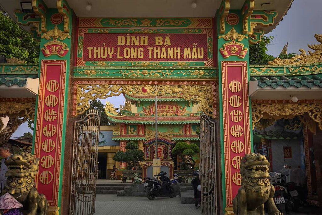 Main gate of Dinh Ba Thuy Long Thanh Mau Temple in Phu Quoc with detailed carvings golden statues red pillars and traditional Vietnamese entrance design