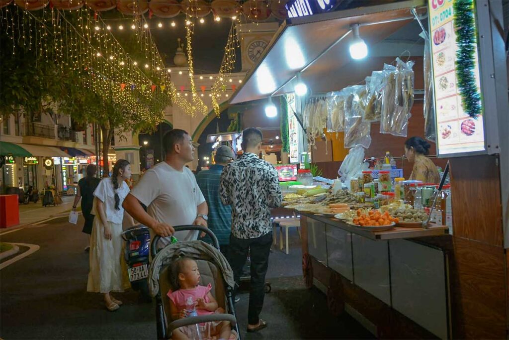 Visitors walking through the Grand World Phu Quoc night market with local food stalls and evening lights in northern Phu Quoc