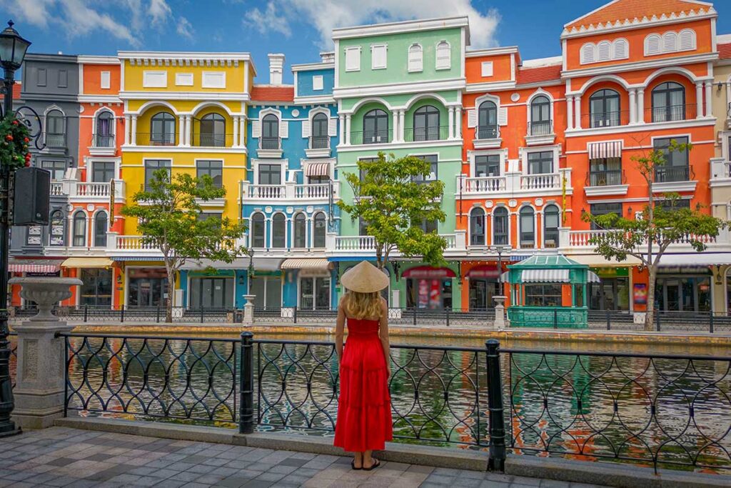 Tourist wearing a traditional Vietnamese hat looking over the colorful canal area at Grand World Phu Quoc