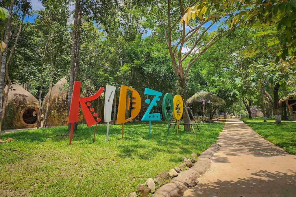 Colorful KidZoo sign and walking paths surrounded by tropical trees at Vinpearl Safari Phu Quoc family activity area