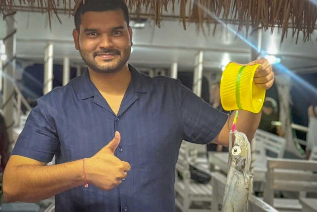 Night squid fishing tour in Phu Quoc with traveler holding freshly caught squid during an evening boat trip on the sea