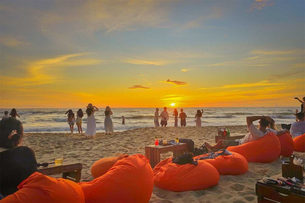 Sunset at OCSEN Beach Bar and Club in Phu Quoc with bean bags on the beach, cocktails, and travelers watching the ocean