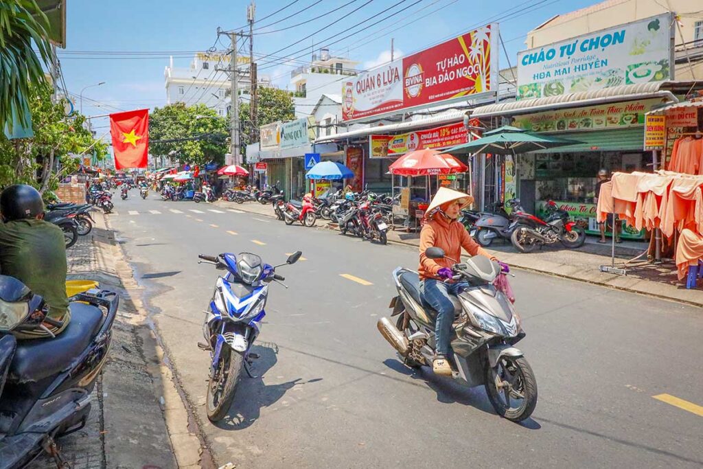 Motorbikes and scooters on a busy street in Duong Dong town, Phu Quoc, with local shops and Vietnamese street signs in the background
