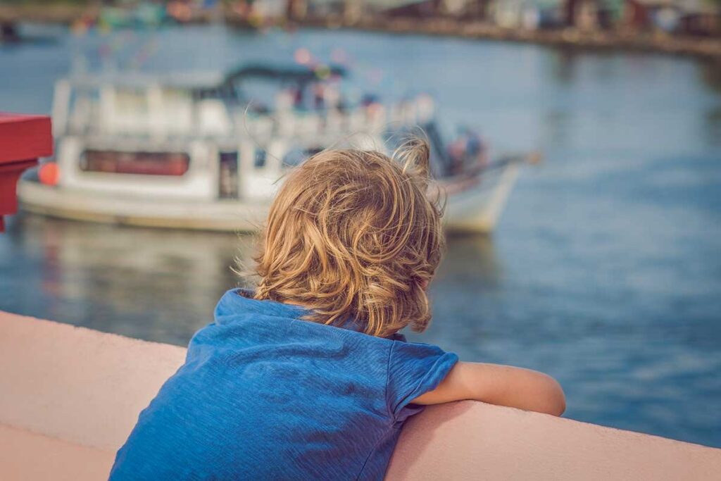 Young child watching fishing boats in Phu Quoc harbor during a family trip in Vietnam
