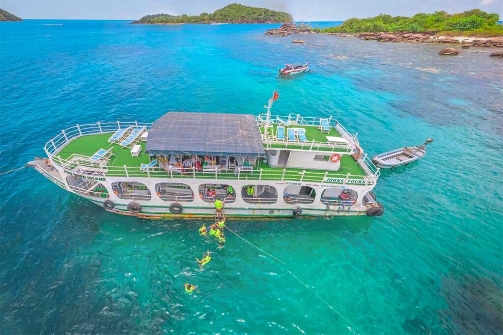 Large island hopping boat anchored above coral reefs during a snorkeling tour in the An Thoi islands of Phu Quoc