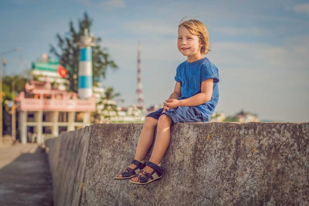 Young child sitting near Dinh Cau Temple and lighthouse in Phu Quoc during a family trip in Vietnam