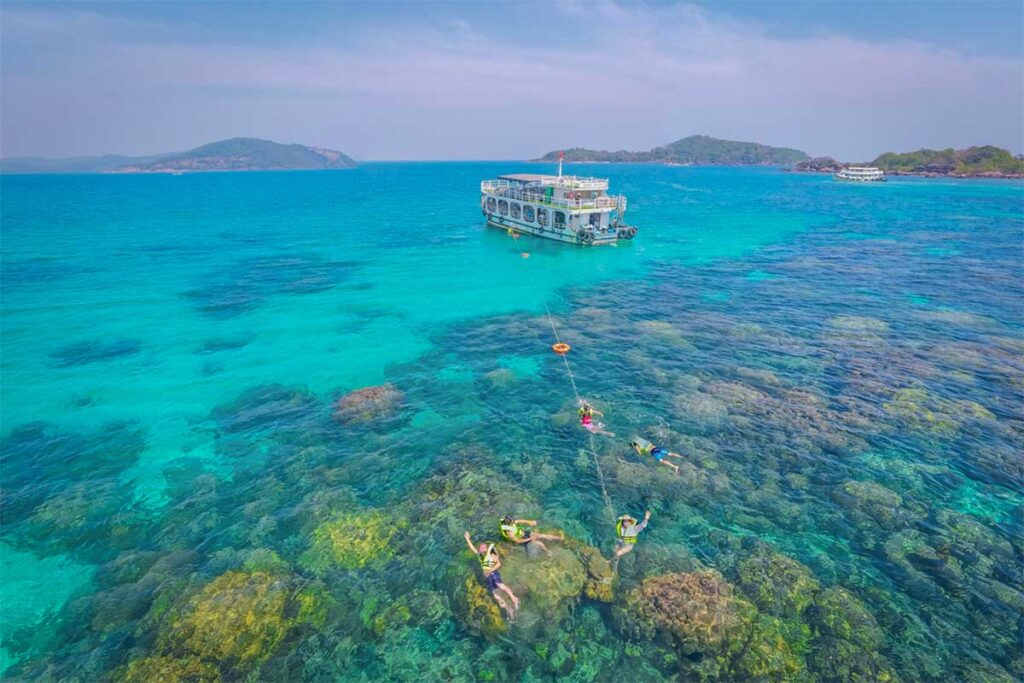 Snorkeling boat trip in Phu Quoc with travelers floating above shallow coral reefs in crystal clear sea water